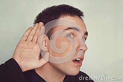 Portrait of young casual man which overhears conversation. concept of deafness or eavesdropping. Hard of hearing. Stock Photo