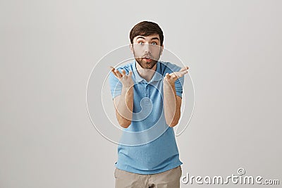 Portrait of young caucasian bearded man bending towards camera with raised palms, looking shocked and amazed with lifted Stock Photo