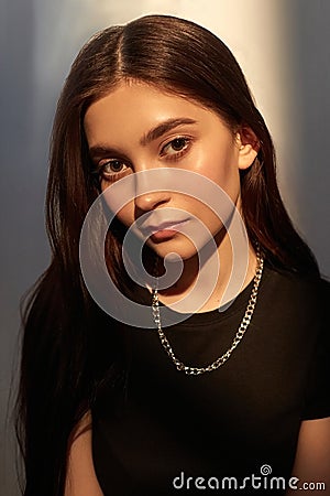 portrait of young caucasian lady with long hair, metal shiny chain in black top Stock Photo