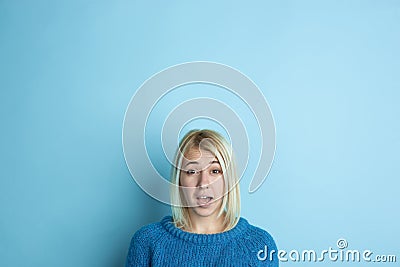 Portrait of young caucasian woman looks happy, dreamful on blue background Stock Photo