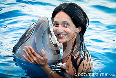 Portrait of young Caucasian woman smile with dolphin look to camera in pool water of Batumi delphinarium. Swim with dolphin Stock Photo