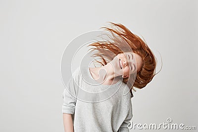 Portrait of young cheerful beautiful redhead girl smiling with closed eyes shaking head and hair over white background. Stock Photo