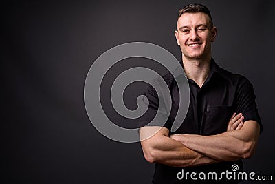 Portrait of young confident businessman smiling with arms crossed looking at camera Stock Photo