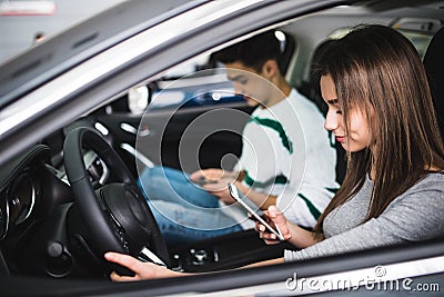 Portrait of a young couple use phones, texting and driving together, as seen through the windshield Stock Photo