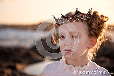 Portrait of a young capricious princess in the rays of the rising sun in the crown Stock Photo