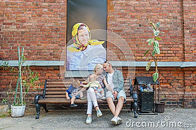 Portrait of a young family against the background red brick wall with picture. Editorial Stock Photo