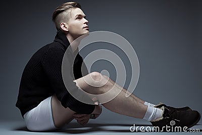 Portrait of young fashionable man in trendy clothes sitting Stock Photo