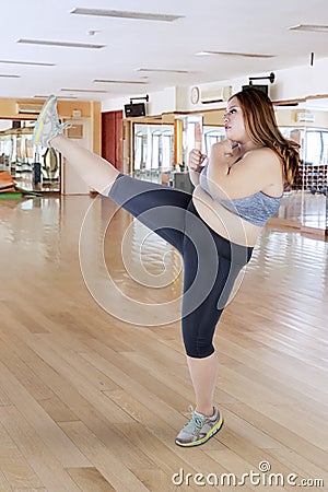 Fat woman performing a kick in gym center Stock Photo