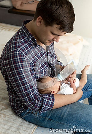 Portrait of young father feeding newborn son with milk Stock Photo