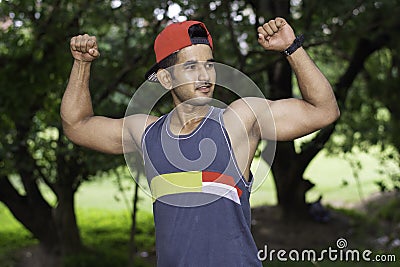 Portrait of Young fit Caucasian man with muscular body showing biceps outdoors on sunny summer day Stock Photo