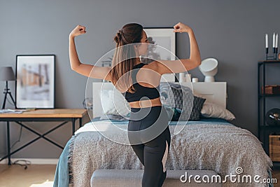 Portrait of young fitness woman showing muscles. Back view. Stock Photo