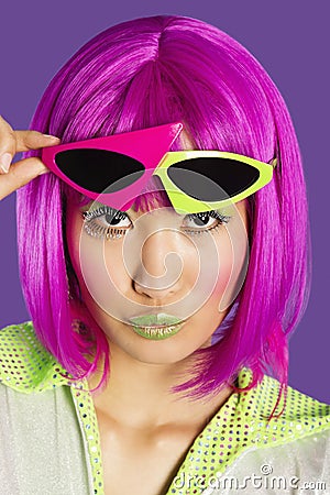Portrait of young funky woman in pink wig puckering lips over purple background Stock Photo