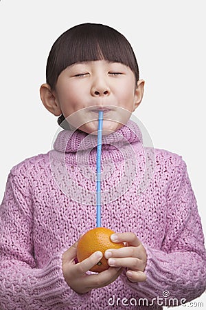 Portrait of young girl with bangs and eyes closed drinking an orange with a straw, studio shot Stock Photo