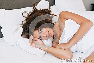 Portrait young girl on bed in modern apartment in the morning. She is looking to camera. Stock Photo