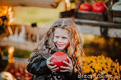 Portrait of young girl holding red pumpkin at the open market place. Autumn background Stock Photo
