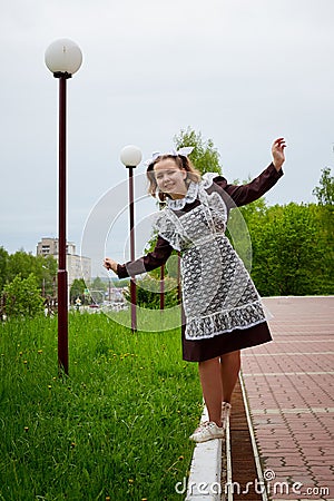 Portrait of a young girl in an old school uniform of the USSR with a black dress and a white apron. Teenager in the Park among Stock Photo