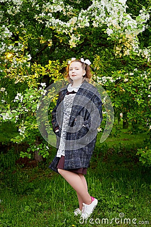 Portrait of a young girl in an old school uniform of the USSR with a black dress and a white apron. Teenager in the Park among the Stock Photo