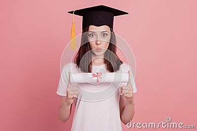 Portrait of young girl pouted lips hold diploma mortarboard graduation isolated over pink pastel color background Stock Photo