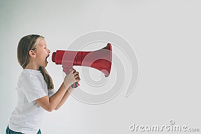 Portrait of young girl shouting using megaphone over background Chil in white shirt, studio shot Stock Photo