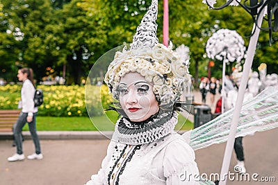 Portrait of a young girl in a white outfit and creative image. Street performer walking on holiday. Makeup and red lipstick on the Editorial Stock Photo