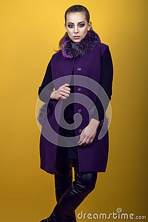 Portrait of young gorgeous model with ponytail and artistic make-up wearing black leather pants and trendy purple sleeveless coat Stock Photo