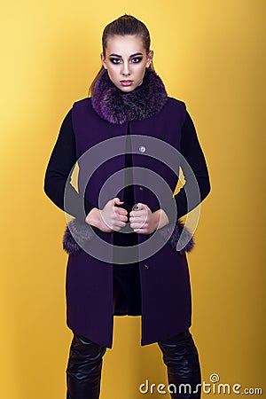 Portrait of young gorgeous model with ponytail and artistic make-up wearing black leather pants and trendy purple sleeveless coat Stock Photo