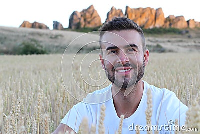 Portrait of a young gorgeous natural man sitting in a wheat field Stock Photo