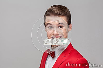 Portrait of young greedy businessman holding dollar banknote with teeth, grinning, money-hungry Stock Photo