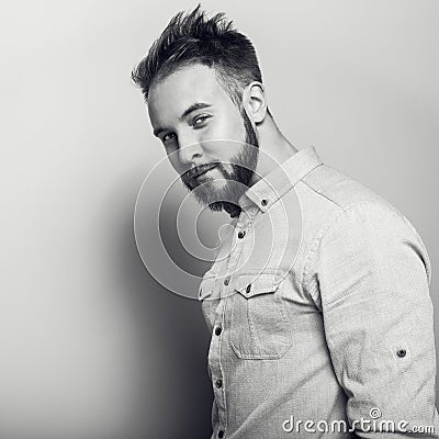 Portrait of young handsome friendly man in bright shirt. Black-white studio photo on light grey background. Stock Photo