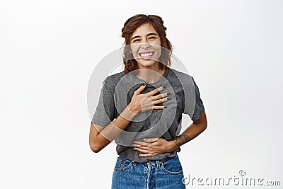 Portrait of young happy woman laughing and smiling, genuine emotions, watching smth funny, chuckle, standing in grey Stock Photo