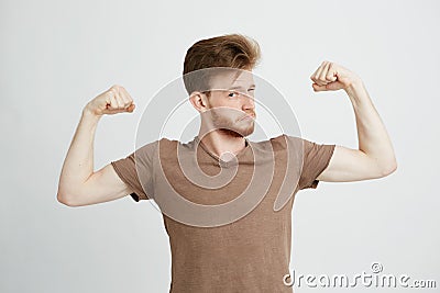 Portrait of young healthy sportive man showing biceps muscles boasting looking at camera over white background. Stock Photo