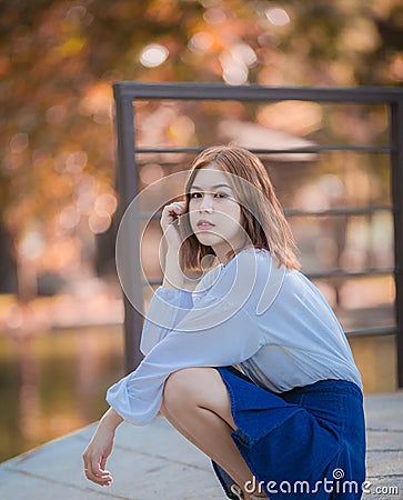 Portrait of young hipster Asian girl posing in the autume park forest background Stock Photo