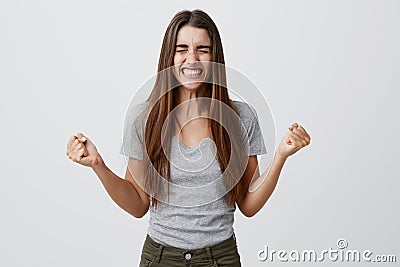 Portrait of young joyful happy beautiful female student with long dark hair in casual gray outfit smiling with teeth Stock Photo