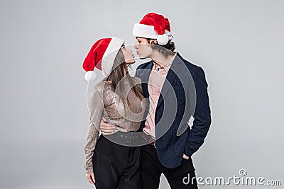 Portrait of young kissing couple in Christmas hats over white background Stock Photo