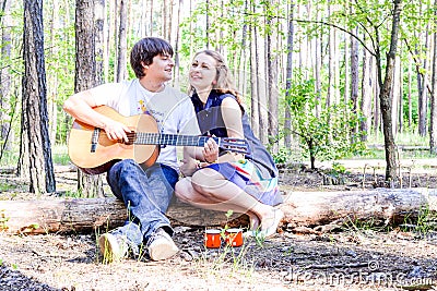 Portrait of young loving happy couple with guitar in forest. Stock Photo