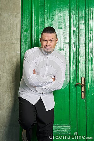 Portrait of a young man, in black slacks and white shirt, green door Stock Photo