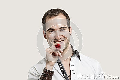 Portrait of young man blowing party puffer against gray background Stock Photo