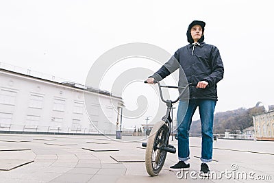 Young man standing with a BMX bike against the city background. BMX rider stands with a bike. BMX concept Stock Photo