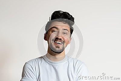 Portrait of a young man with braces smiling and laughing. A happy young man with braces on a white background Stock Photo