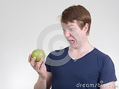 Portrait of young man looking disgusted while holding apple Stock Photo