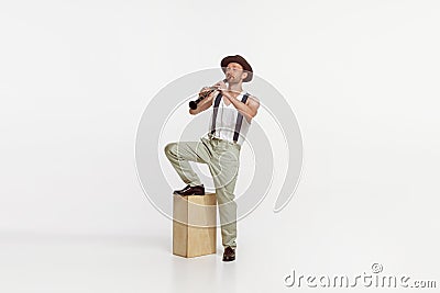 Portrait of young man playing clarinet isolated over white studio background. Countryside singer performing Stock Photo