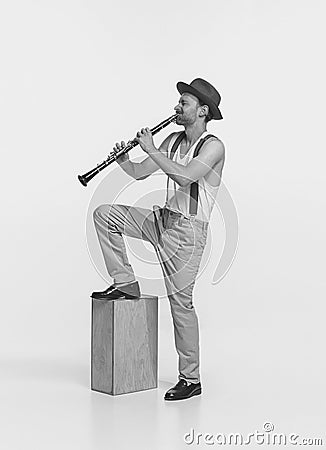 Portrait of young man playing clarinet isolated over white studio background. Expressive performance. Black and white Stock Photo