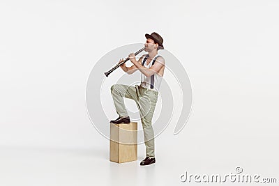 Portrait of young man playing clarinet isolated over white studio background. Expressive performance Stock Photo