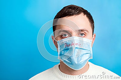 Portrait of young man in protective mask with pandemic text at blue background. and health care concept Stock Photo