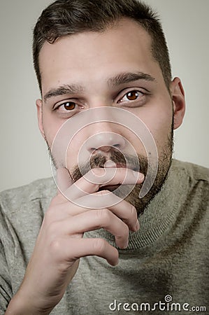 Portrait of a young man with a short beard in a moment of reflection with his hand to his chin Stock Photo