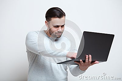 Portrait of young man typing on laptop keyboard over white background Stock Photo