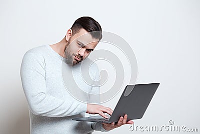 Portrait of young man typing on laptop keyboard over white background Stock Photo