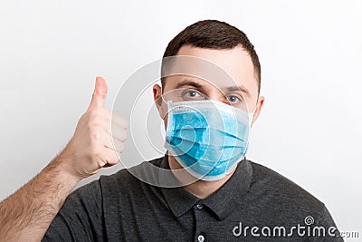 Portrait of young man wearing a medical mask at white background. Person is happy because he is finally healthy. Coronavirus Stock Photo
