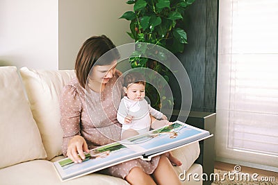 Portrait of young mother and adorable baby watching family album together Stock Photo