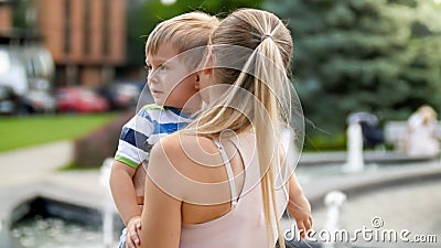 Closeup portrait of young mother hugging and caressing her crying little child boy in park Stock Photo